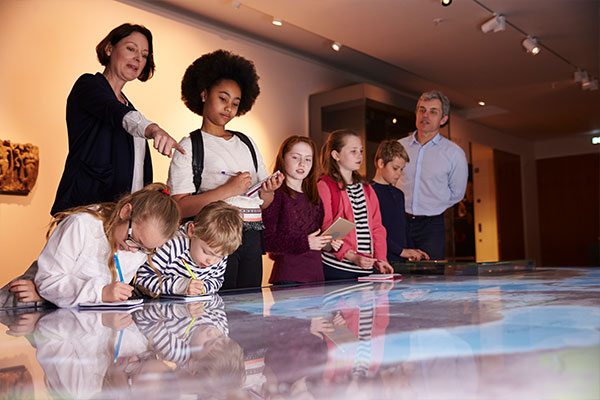group of students and teachers taking notes at a museum 